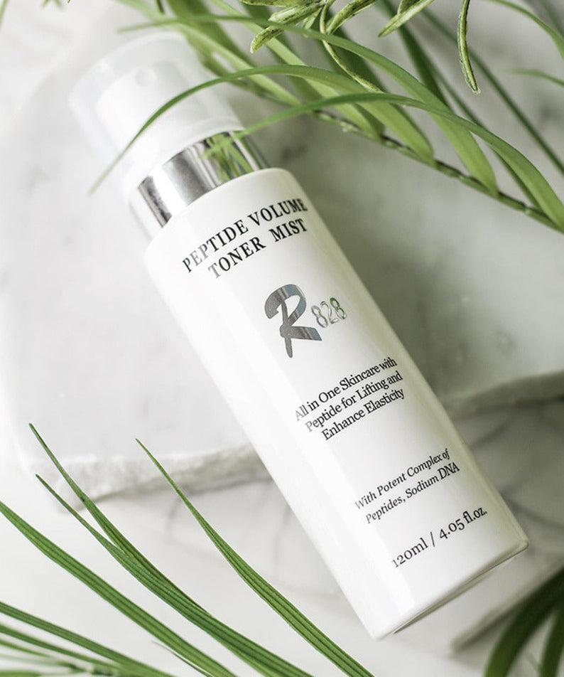 R828 Peptide Volume Toner Mist bottle on white background with green leaves