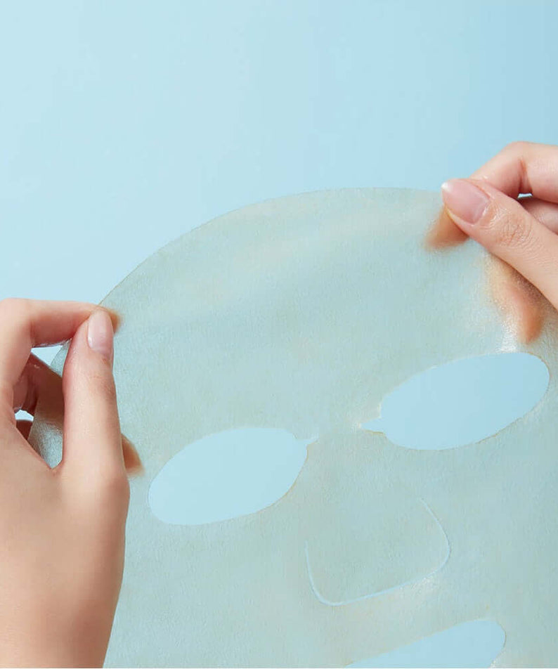 REAL BARRIER Cica Relief Rx Fade-In Serum Mask 10 Sheets being held by hands against a light blue background