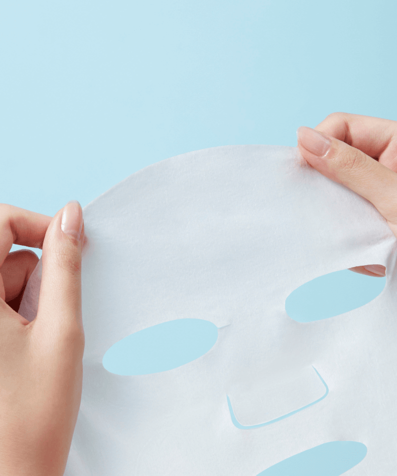 Holding REAL BARRIER Extreme Cream Mask 10 Sheets against light blue background
