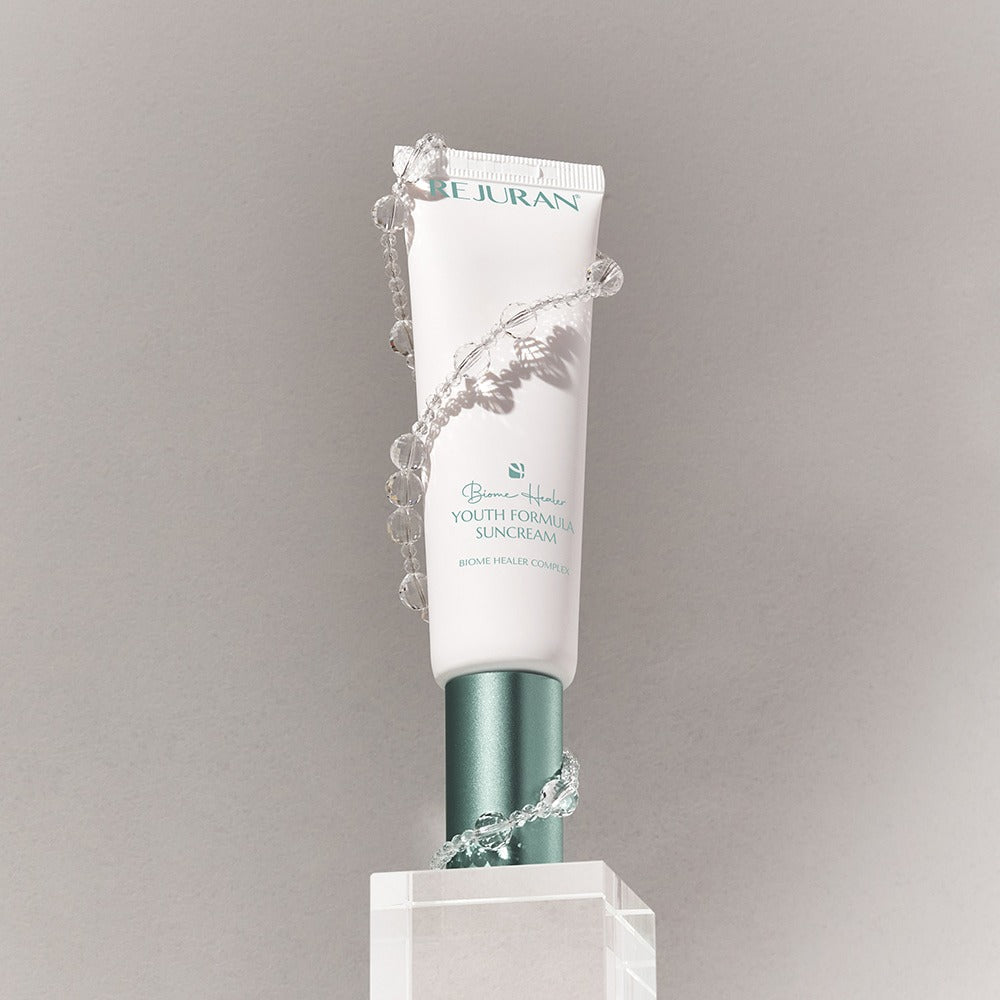 REJURAN Biome Healer Touth Formula Sunscreen 50ml displayed with decorative elements.