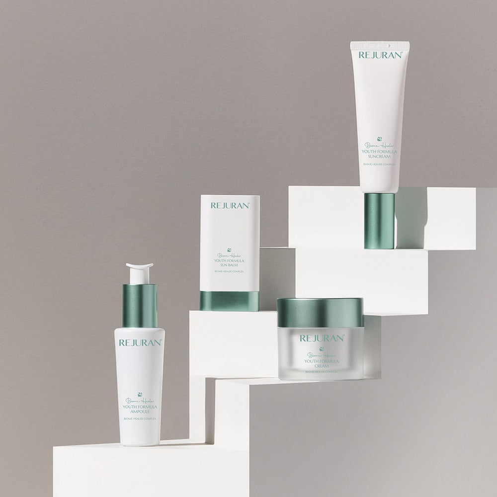 REJURAN Biome Healer Touth Formula Sunscreen 50ml displayed with skincare products on geometric stands