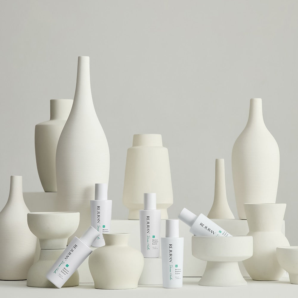 REJURAN Derma Healer Moisture Treatment Essence 70g displayed among artistic white vases.