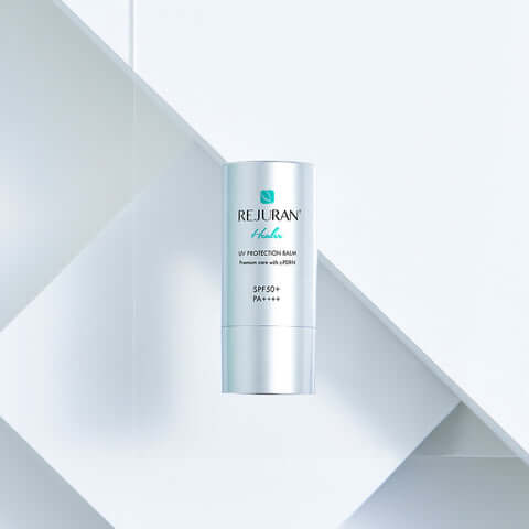 REJURAN Healer UV Protection Balm 19g displayed on a geometric background for skincare and sun protection with SPF50+