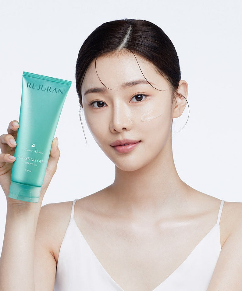 Woman holding REJURAN Premium Beauty Device skin gel tube, demonstrating skincare application on face.