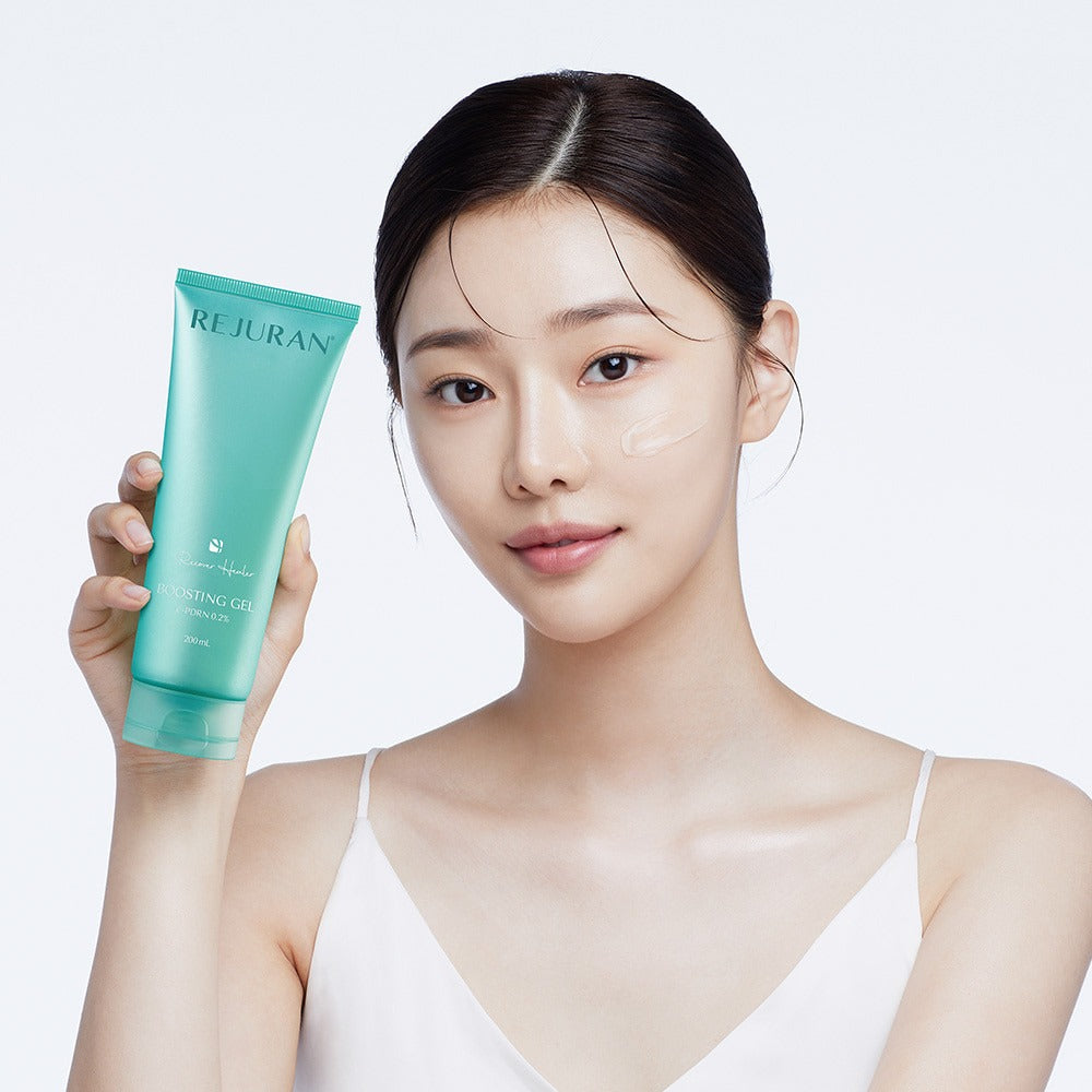 Woman holding REJURAN Premium Beauty Device skin gel tube, demonstrating skincare application on face.