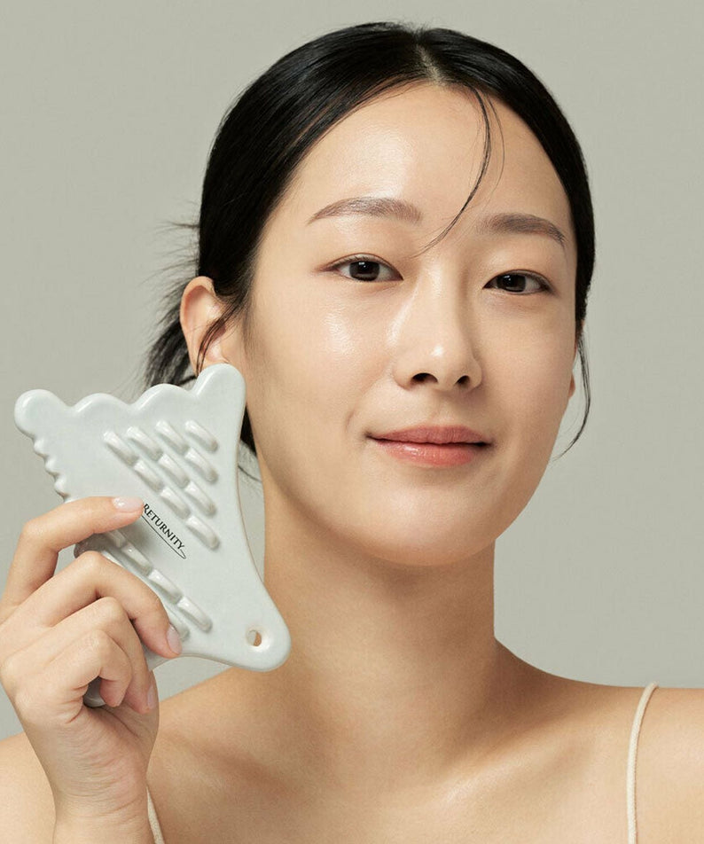 Woman holding RETURNITY Guasha tool.