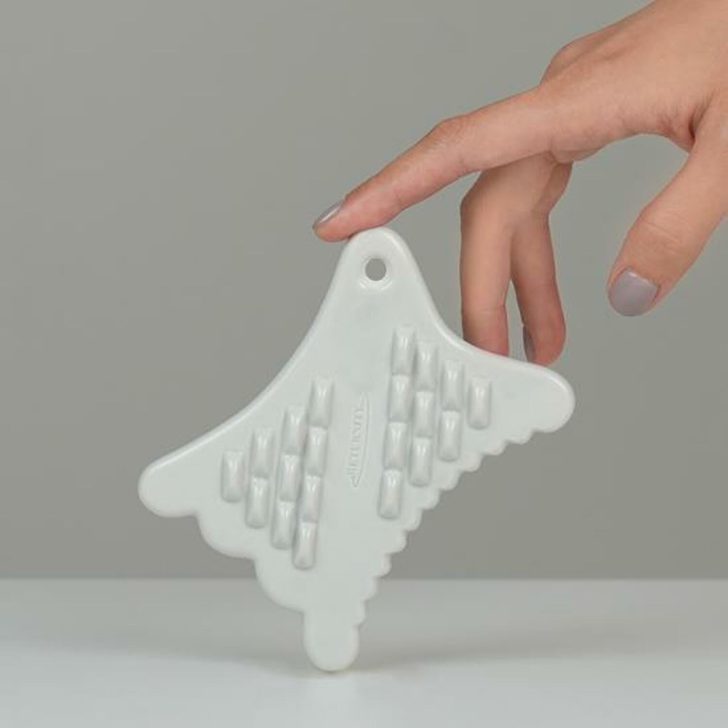 Hand holding RETURNITY Mini Guasha tool on a gray background, showcasing its design and features for effective skincare treatment.