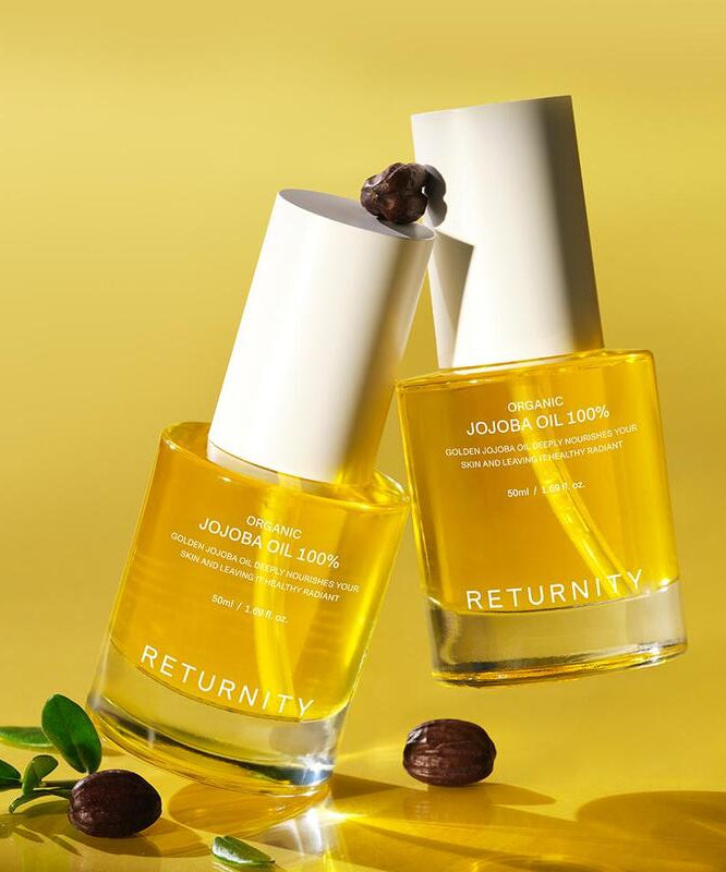RETURNITY Organic Jojoba Oil 100% 50ml bottle on a yellow background with jojoba seeds and leaves.