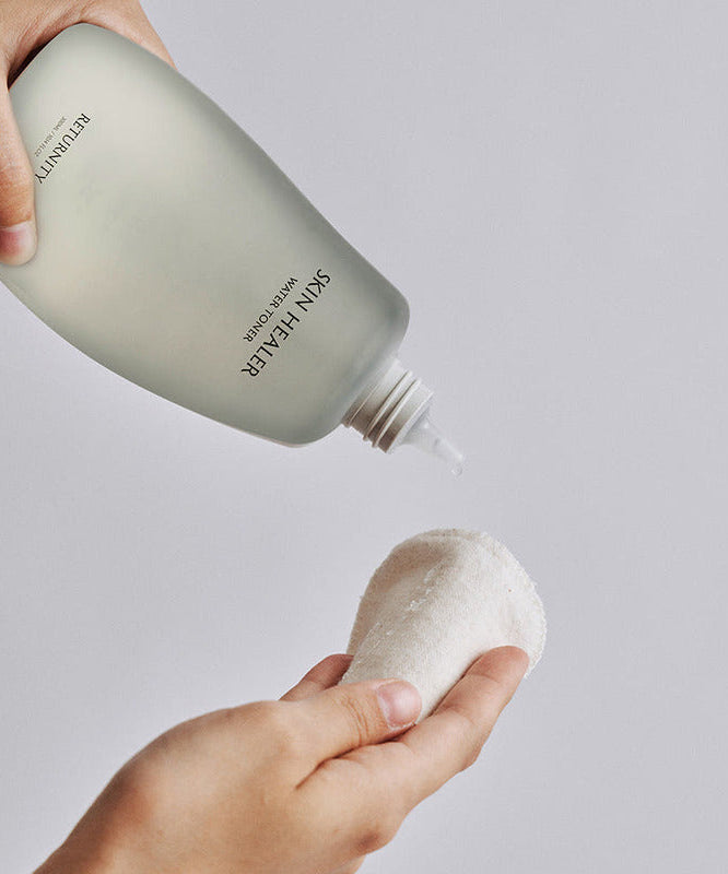 Person using RETURNITY Skin Healer Water Toner 300ml on a cotton pad for skincare routine.