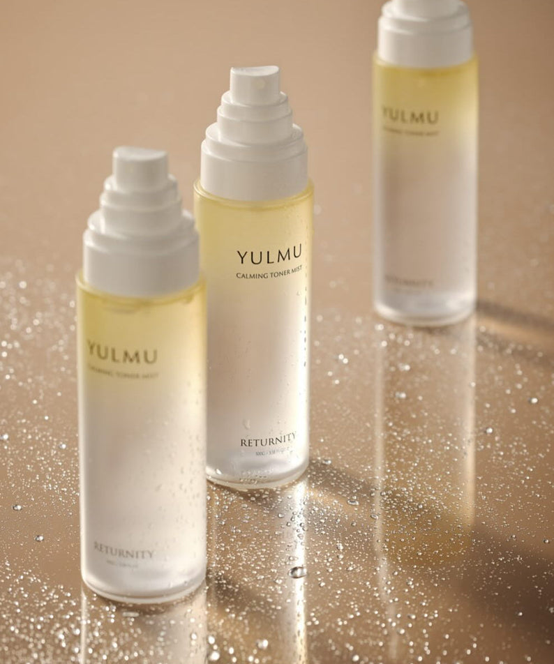 Three bottles of RETURNITY Yulmu Calming Toner Mist 100ml on a reflective surface.