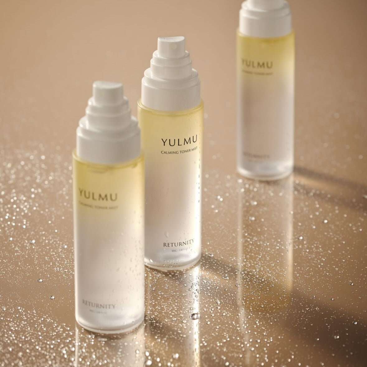 Three bottles of RETURNITY Yulmu Calming Toner Mist 100ml on a reflective surface.