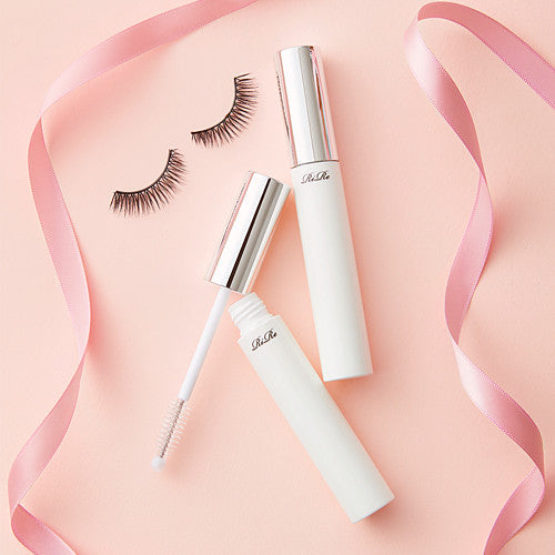 RIRE Luxe Eye Lash Essence on pink background with false eyelashes and pink ribbon, enhancing lash beauty and strength.