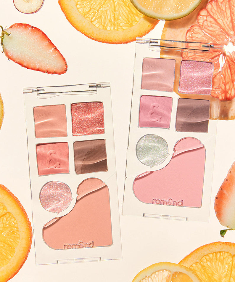ROMAND Bare layer palette surrounded by fresh fruit slices, showcasing vibrant makeup shades and elegant packaging.