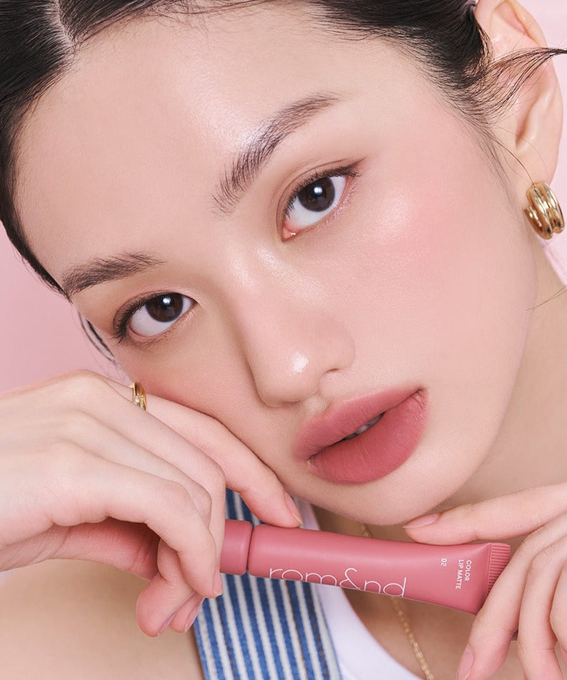 Model showcasing ROMAND Color Lip Matte in a soft pink shade, highlighting the product's sleek design and vibrant color