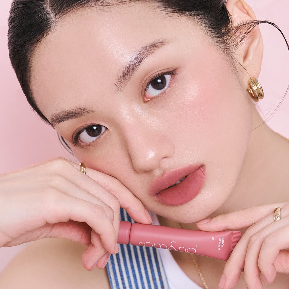 Model showcasing ROMAND Color Lip Matte in a soft pink shade, highlighting the product's sleek design and vibrant color