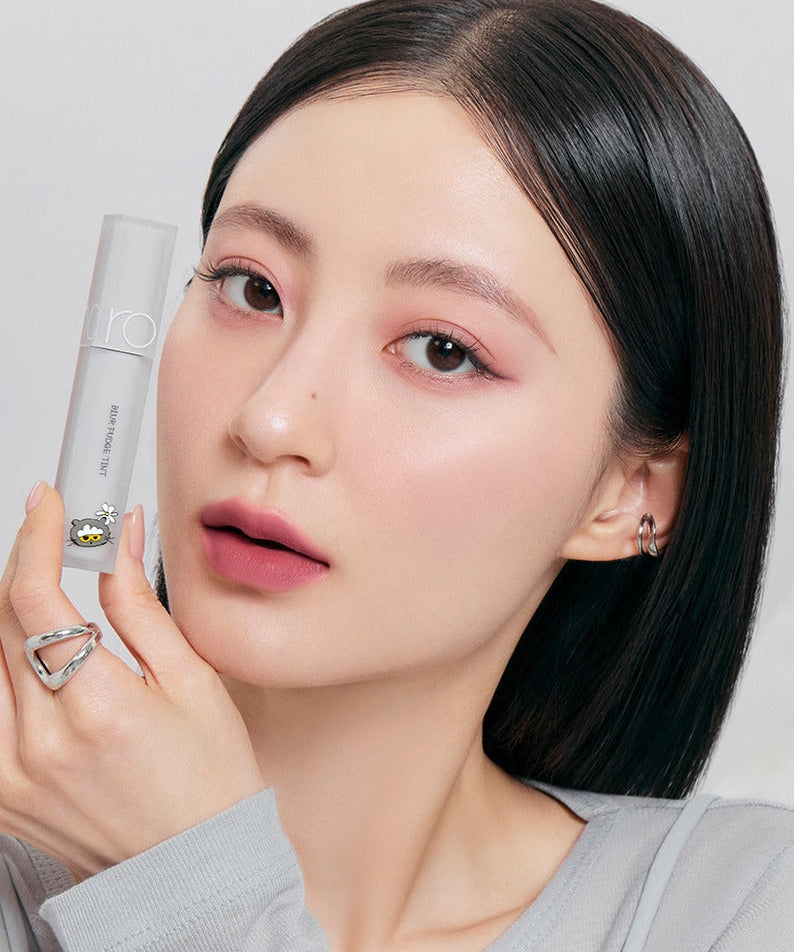 Woman holding ROMAND x Joanne Friends Blur Fudge Tint, showcasing the lip tint color and packaging.