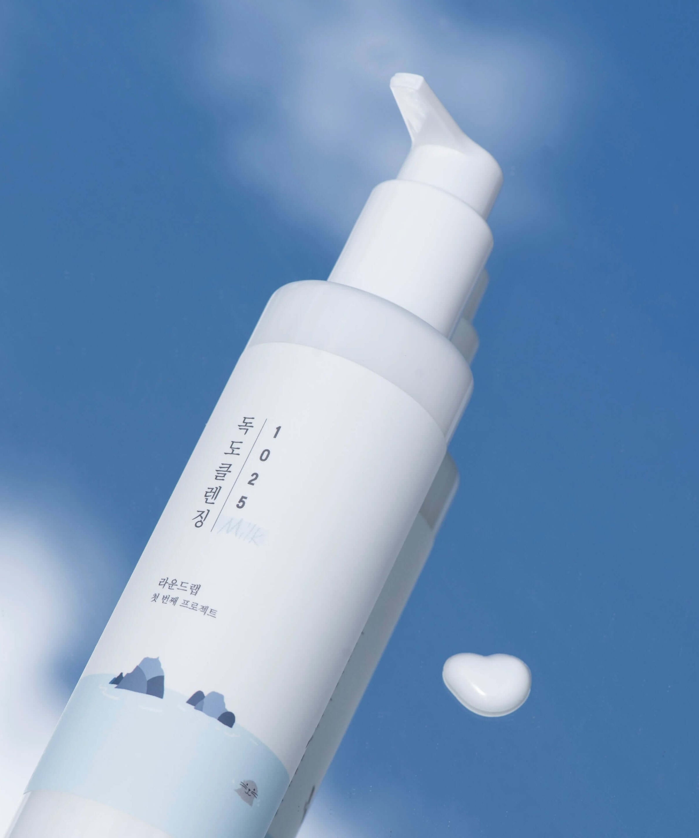 Bottle of ROUND LAB 1025 Dokdo Cleansing Milk 200ml against a blue sky background.