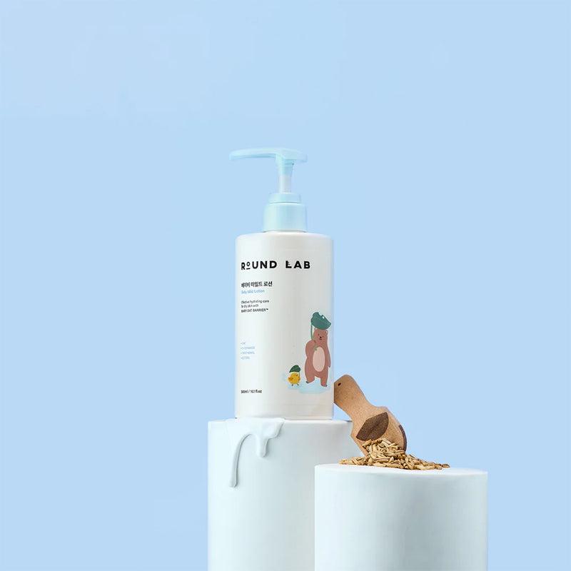 ROUND LAB Baby Mild Lotion 300ml bottle displayed with natural ingredients on a light blue background.