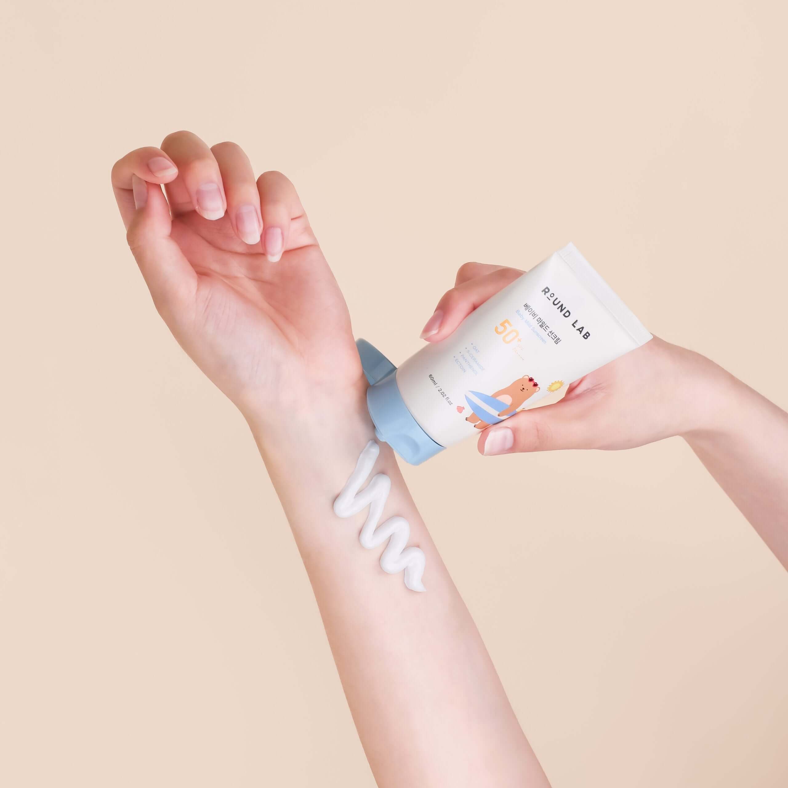 Applying ROUND LAB Baby Mild Sun Cream 60ml to arm for gentle sun protection.