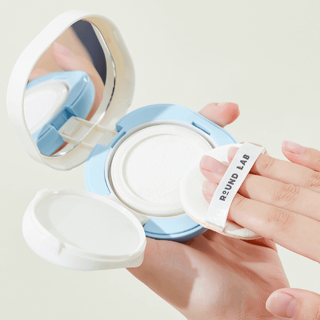 Application of ROUND LAB Baby Mild Sun Cushion 16g with puff applicator showcasing its compact design.