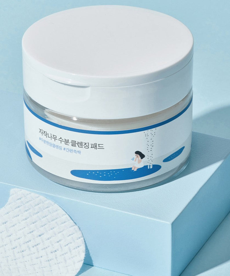 ROUND LAB Birch Juice Moisturizing Cleansing Pad 60p 210g container on blue surface with cleansing pad detail