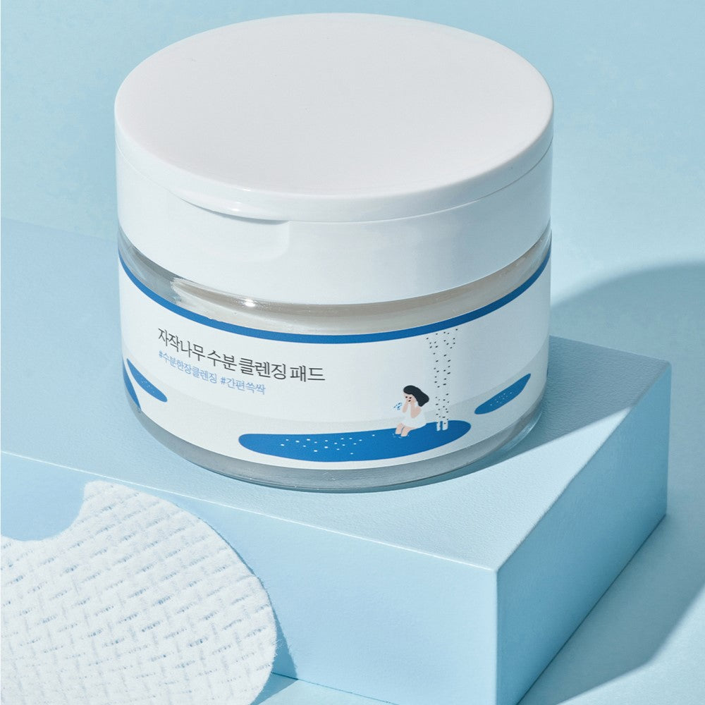 ROUND LAB Birch Juice Moisturizing Cleansing Pad 60p 210g container on blue surface with cleansing pad detail