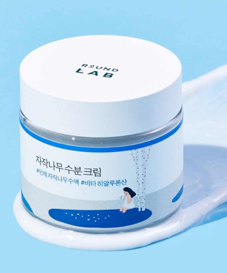 ROUND LAB Birch Juice Moisturizing Cream 80ml in a jar on a textured blue background