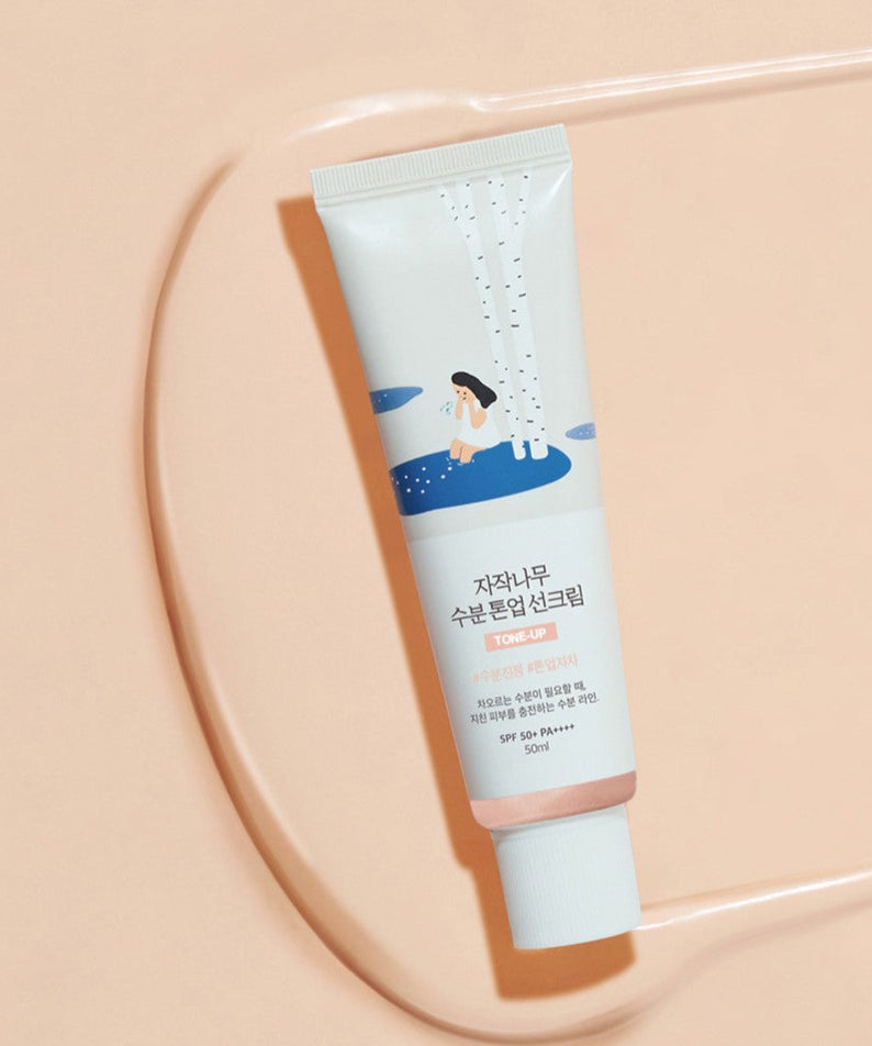 ROUND LAB Birch Juice Moisturizing Tone-up Sunscreen 50ml on beige background with illustration on tube.