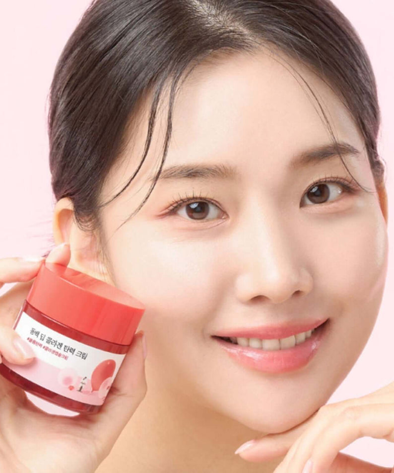 Smiling woman holding ROUND LAB Dongbaek Deep Collagen Elasticity Cream 50ml