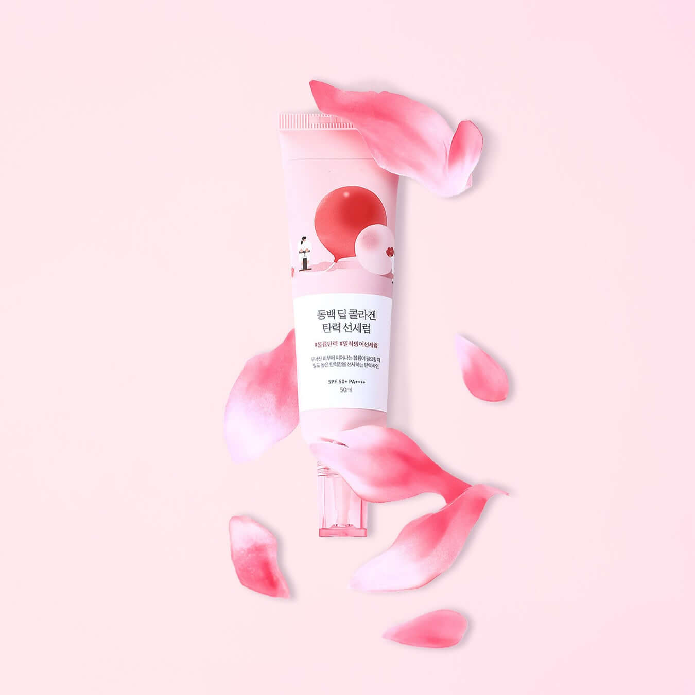 ROUND LAB Dongbaek Deep Collagen Elasticity Sun Serum 50ml surrounded by pink petals on a pastel background