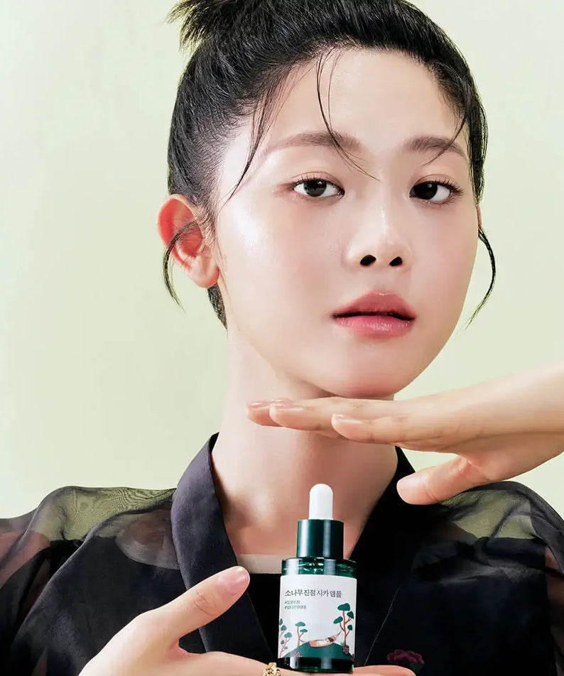 Woman holding ROUND LAB Pine Calming Cica Ampoule 30ml, highlighting skincare benefits.