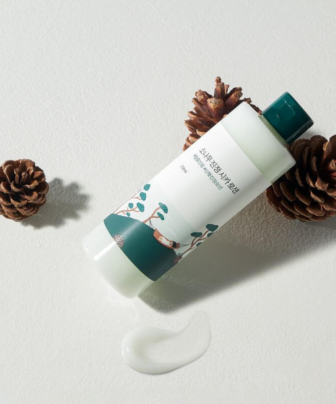 ROUND LAB Pine Calming Cica Lotion 250ml surrounded by pine cones and lotion swatch