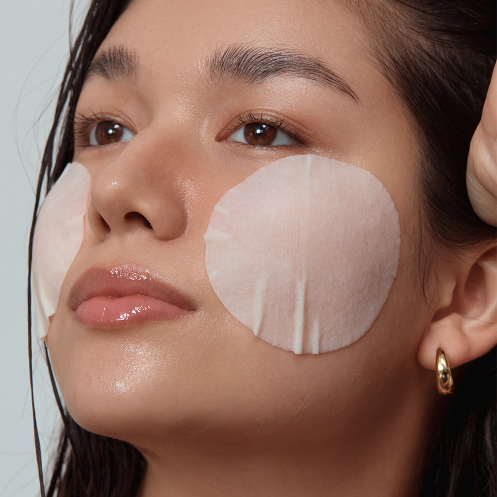 Woman using SHAISHAISHAI Repair Milky Skin Peel Pad 60 Pads 120ml on cheeks for skincare treatment.