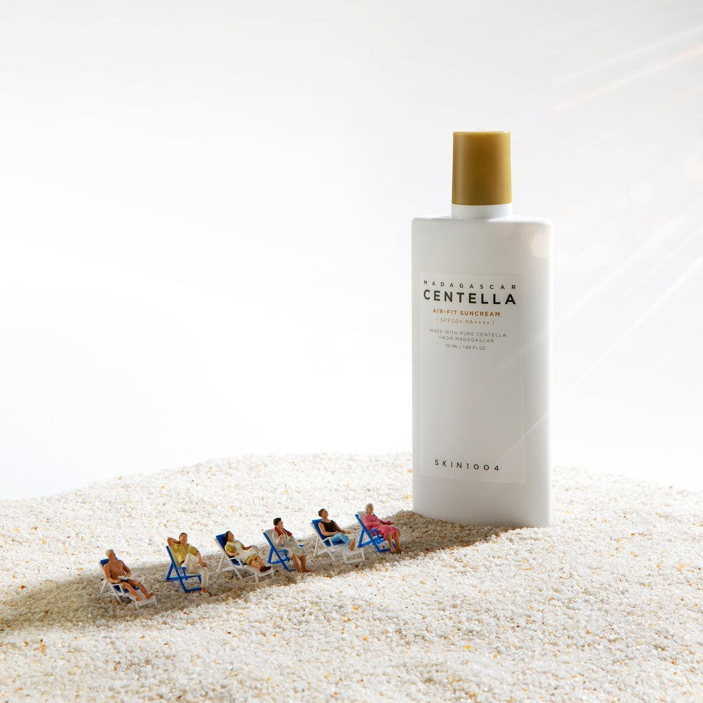 SKIN1004 Madagascar Centella Air-fit Sunscreen Plus 50ml on a sandy beach scene with miniature sunbathers