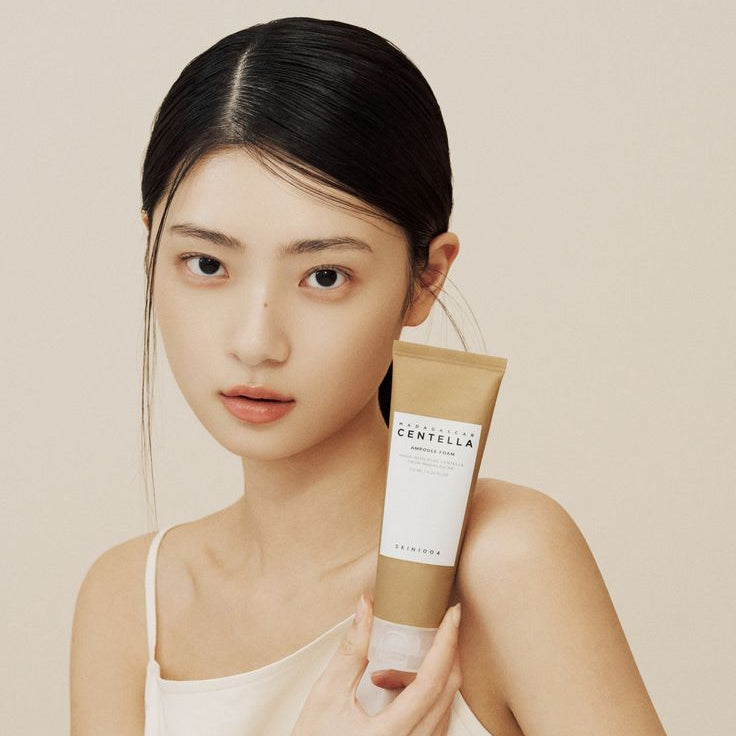 Woman holding tube of SKIN1004 Madagascar Centella Ampoule Foam 125ml.