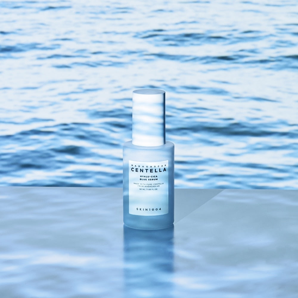 SKIN1004 Madagascar Centella Hyalu-Cica Blue Serum 50ml on a reflective surface with ocean background