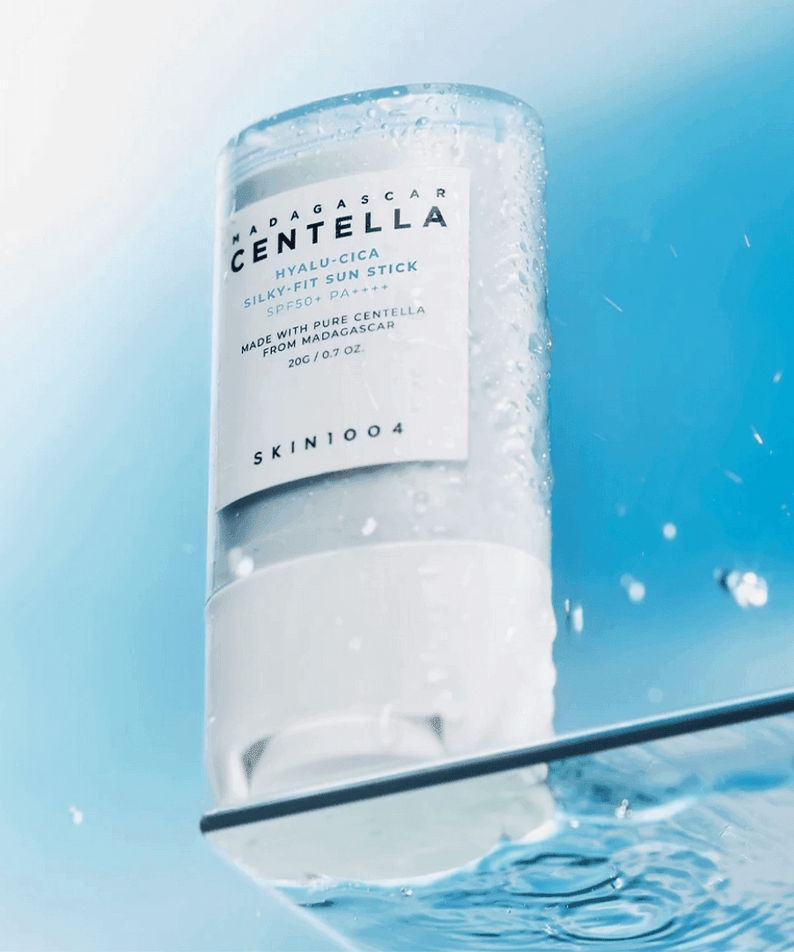 SKIN1004 Madagascar Centella Hyalu-Cica Silky Fit Sun Stick 20g displayed against a blue background with water droplets.