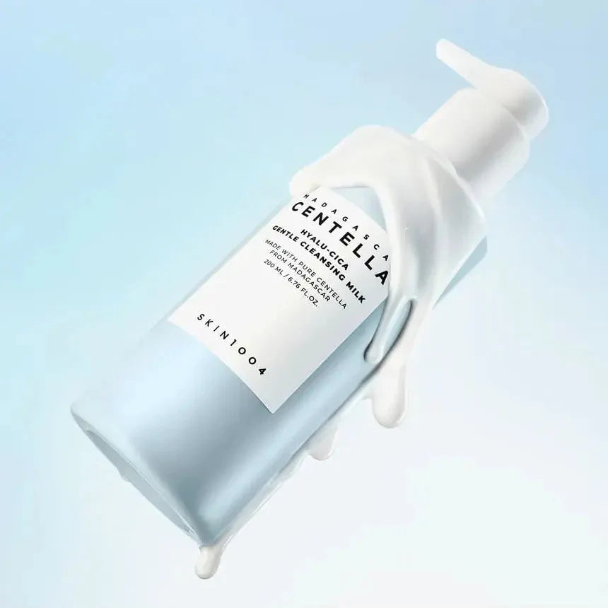 SKIN1004 Madagascar Centella Hyalur-Cica Gentle Cleansing Milk 200ml bottle with product spilling out, against a blue background.