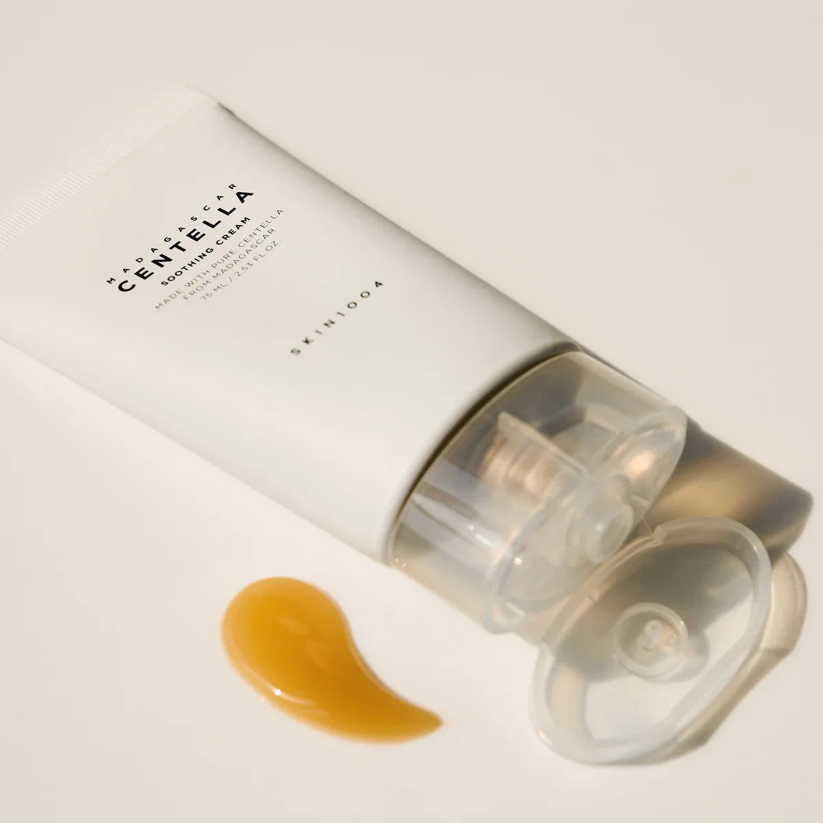 Tube of SKIN1004 Madagascar Centella Soothing Cream 75ml with cream sample next to it on a light background.