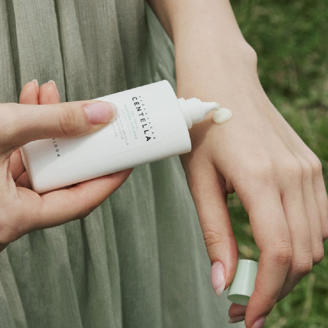 Applying SKIN1004 Madagascar Centella Tea-trica Soothing Sun Milk 50ml on skin outdoors