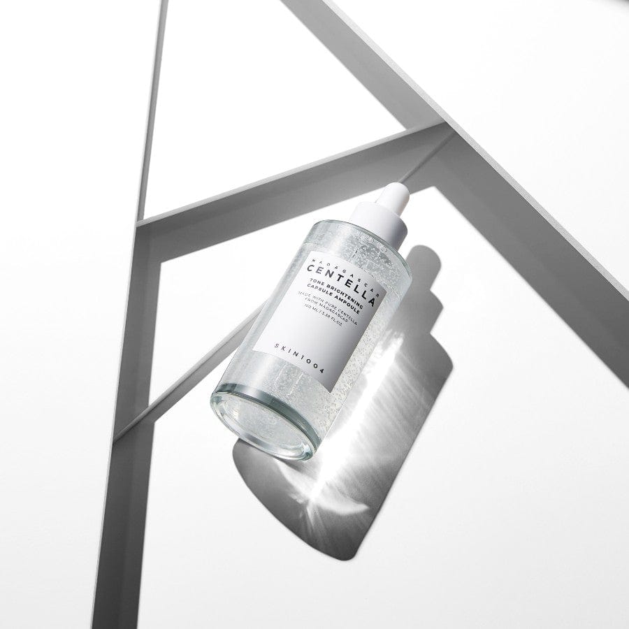 Bottle of SKIN1004 Madagascar Centella Tone Brightening Capsule Ampoule 100ml placed on geometric white background with shadow