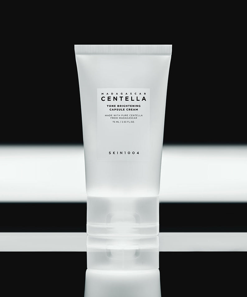 SKIN1004 Madagascar Centella Tone Brightening Capsule Cream 75ml in a sleek tube on reflective black surface.