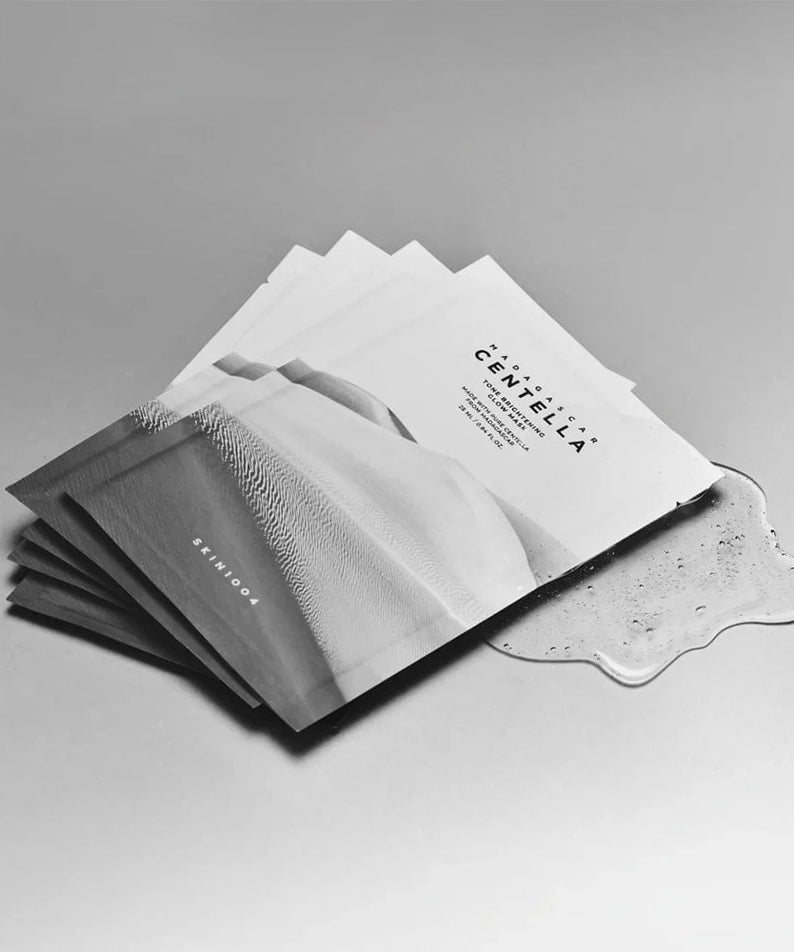 SKIN1004 Madagascar Centella Tone Brightening Glow Mask 25ml [5 sheets] displayed fanned out on a smooth surface.