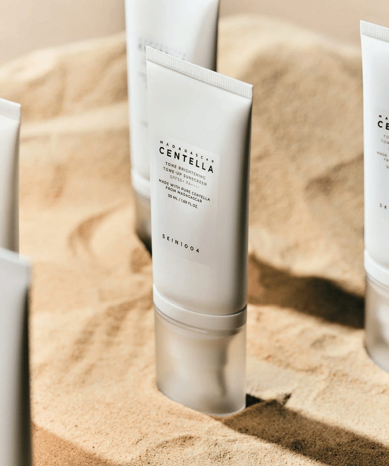 SKIN1004 Madagascar Centella Tone Brightening Tone-Up Sunscreen 50ml displayed on sand background.