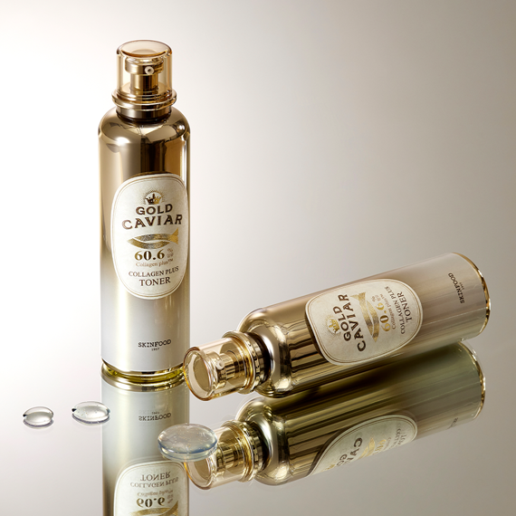 Two bottles of SKINFOOD Gold Caviar Collagen Plus Toner 120ml on a reflective surface showcasing product packaging.