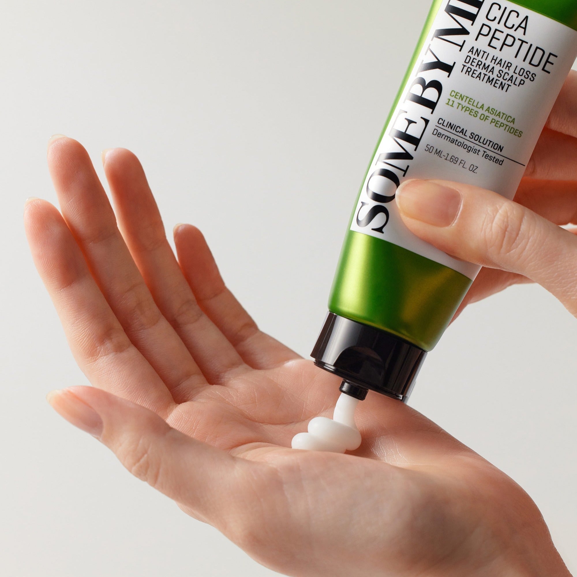 Applying SOME BY MI Cica Peptide Anti Hair Loss Derma Scalp Treatment 50ml from tube to hand for hair care