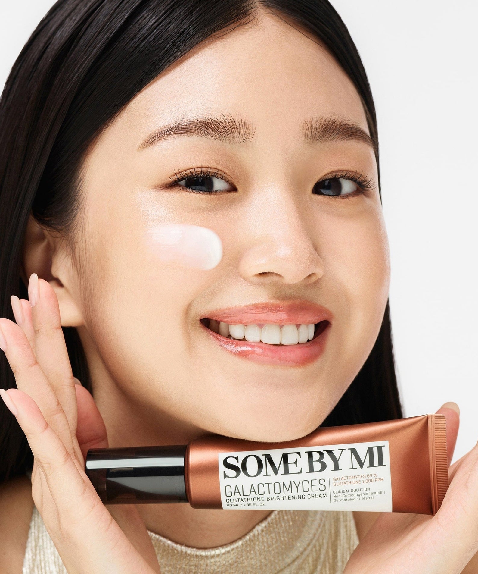 Smiling woman holding SOME BY MI Galactomyces Glutathione Brightening Cream 40ml, showcasing product application.