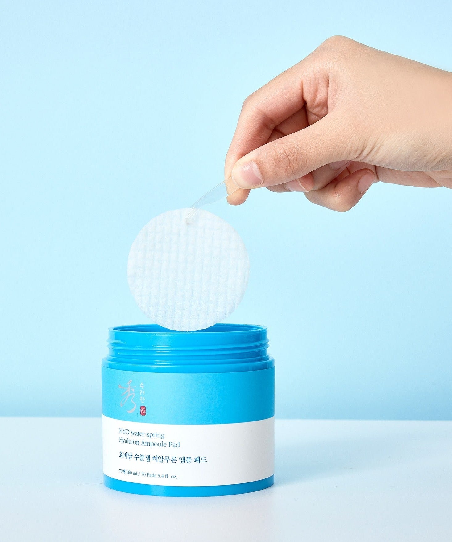 Hand holding a pad from SOORYEHAN Moiture Spring Hyaluronic Ampoule Pads 70 Sheets container