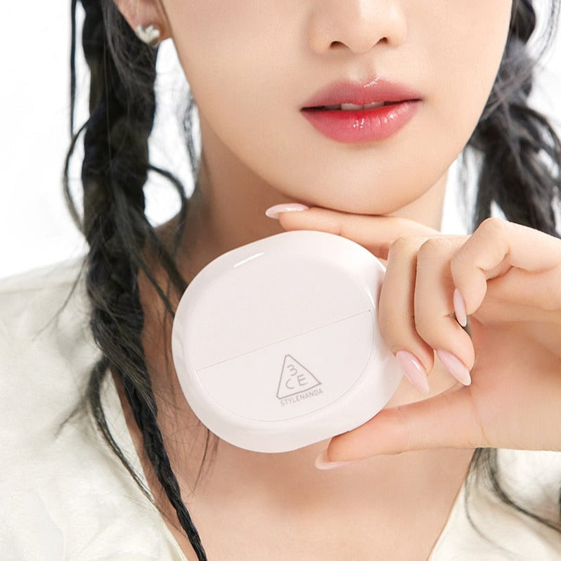 Woman holding STYLE NANDA 3CE Bare Cover Cushion compact close to her face, showcasing product design.