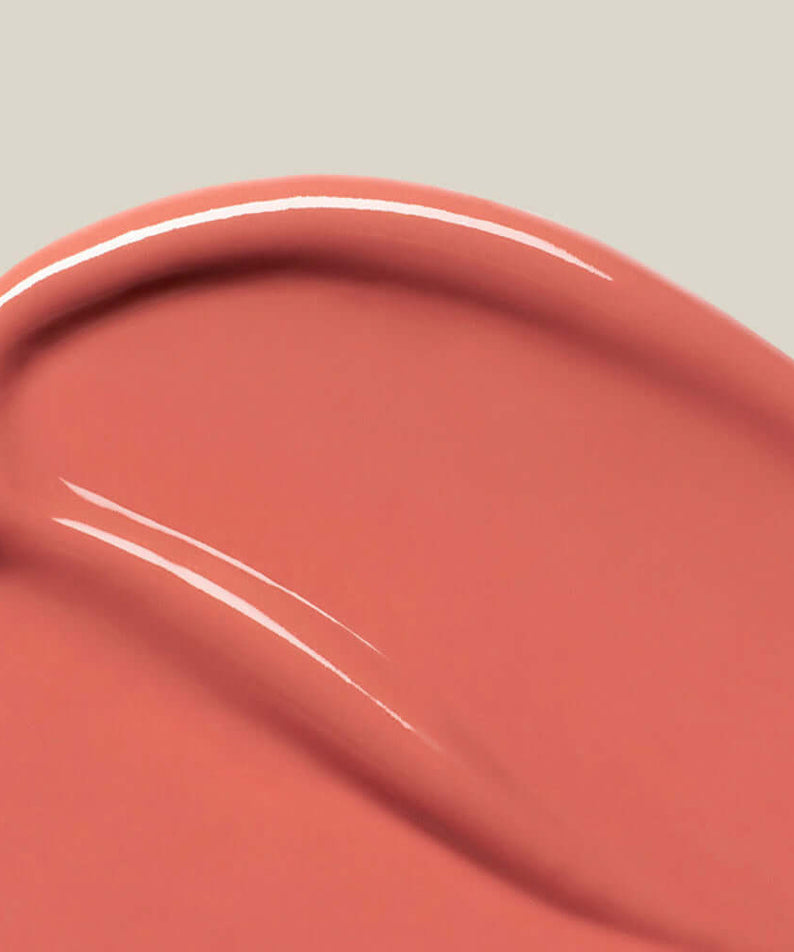 Close-up of SU:M37 Skin-Stay Glossy Lip Balm texture in peachy pink color, showcasing the smooth and glossy finish.